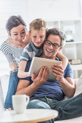 a cheerful family has fun together by playing on a tablet