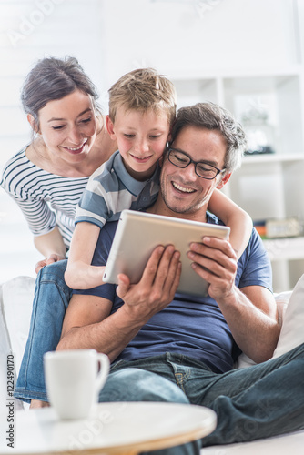 a cheerful family has fun together by playing on a tablet