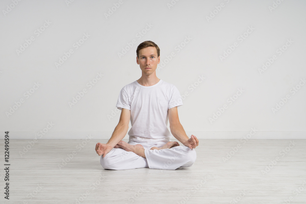 Young man meditating in Lotus position on the floor Young man meditating in Lotus position on the floor
