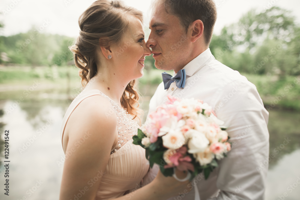 Bride and groom holding beautiful wedding bouquet. Lake, forest Bride and groom holding beautiful wedding bouquet. Lake, forest