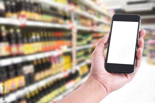 Hand holding smartphone with blank screen in food supermarket store background
