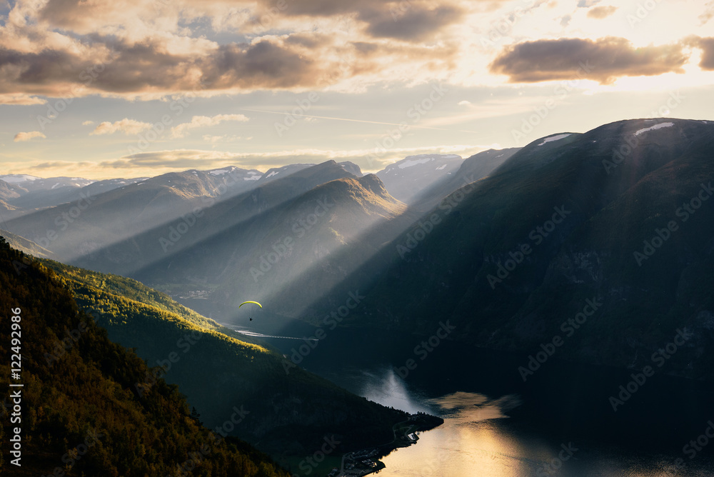 Paraglider silhouette flying over Aurlandfjord, Norway