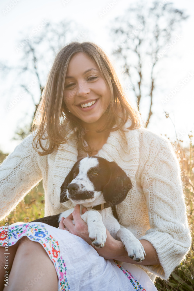 Girl sitting with adorable puppy pionter in field