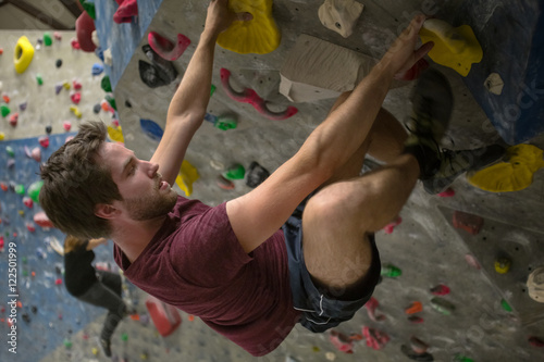 young man climbing in a boulder hall