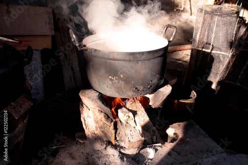 Old pot of food cooking on burning wood fire stove