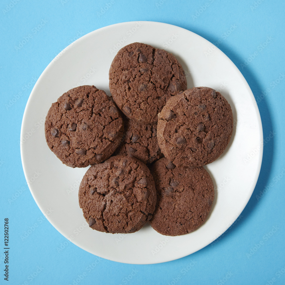 A plate of chocolate chunk cookies on a bright blue background A plate of chocolate chunk cookies on a bright blue background
