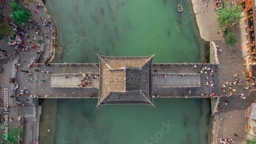 Top View or Aerial Shot of Famous Stone Old Fashioned Chinese Bridge in Ancient Town in Fenghuang County, China. Aerial View of Stone Bridge over Green River, Crowds of People. 