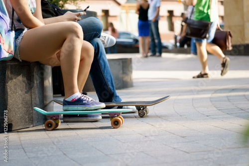 Young person sitting with skateboards and resting on summer day