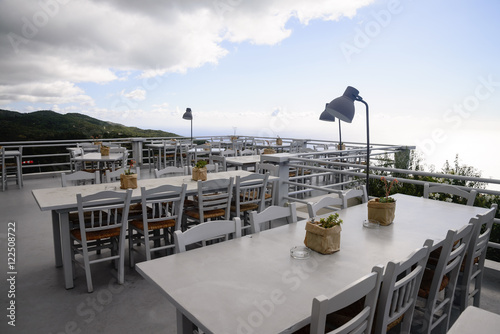 Luxury terrace balcony of exclusive restaurant with retro table and chairs and full sea panorama from the top of the mountain in Greek island Lefkada