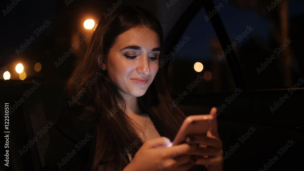 Beautiful girl riding in a taxi at night and read the letter in the smartphone Beautiful girl riding in a taxi at night and read the letter in the smartphone