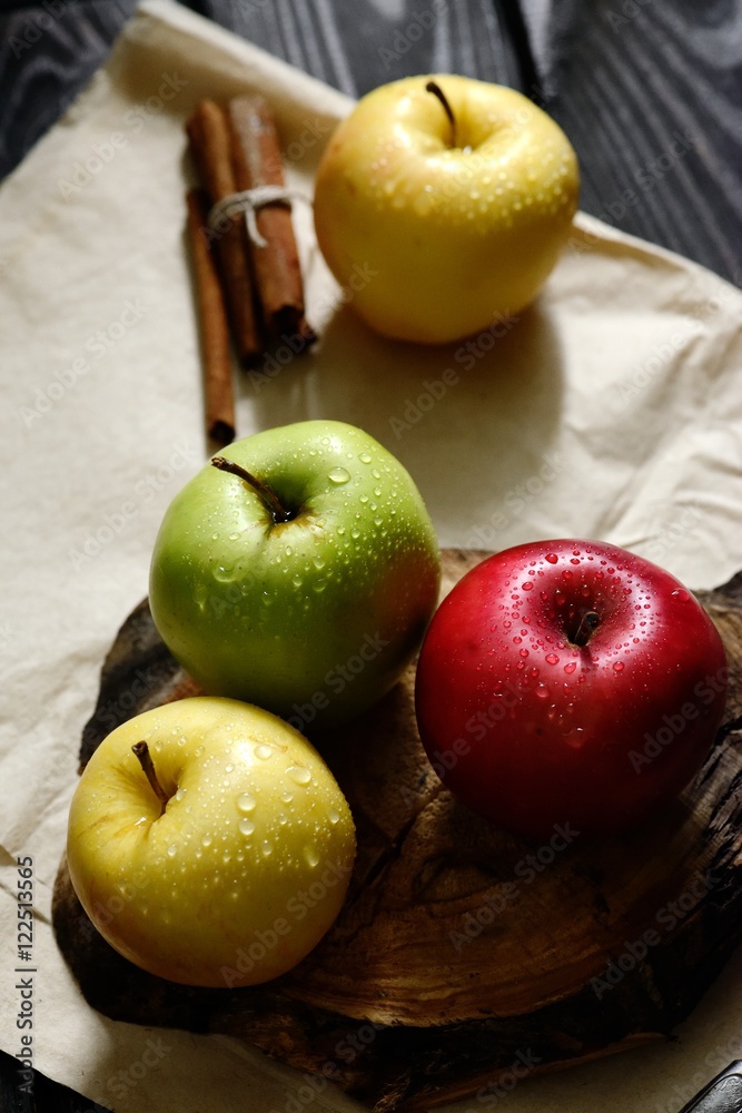 Apples with khife and cinnamon water drops on craft paper black wooden table, back light Apples with khife and cinnamon water drops on craft paper black wooden table, back light