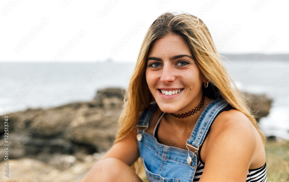 Portrait of smiling teenage girl sitting at the coast Portrait of smiling teenage girl sitting at the coast