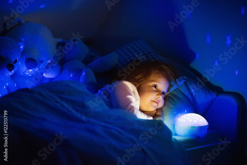 Little girl in bed with night lamp photo