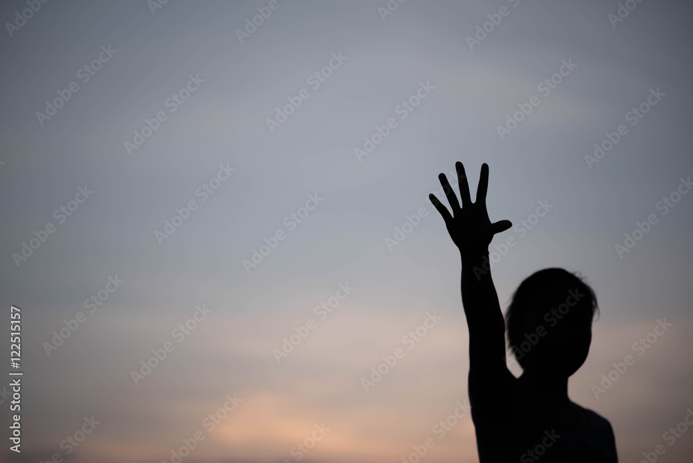 silhouette woman hand up at sunset