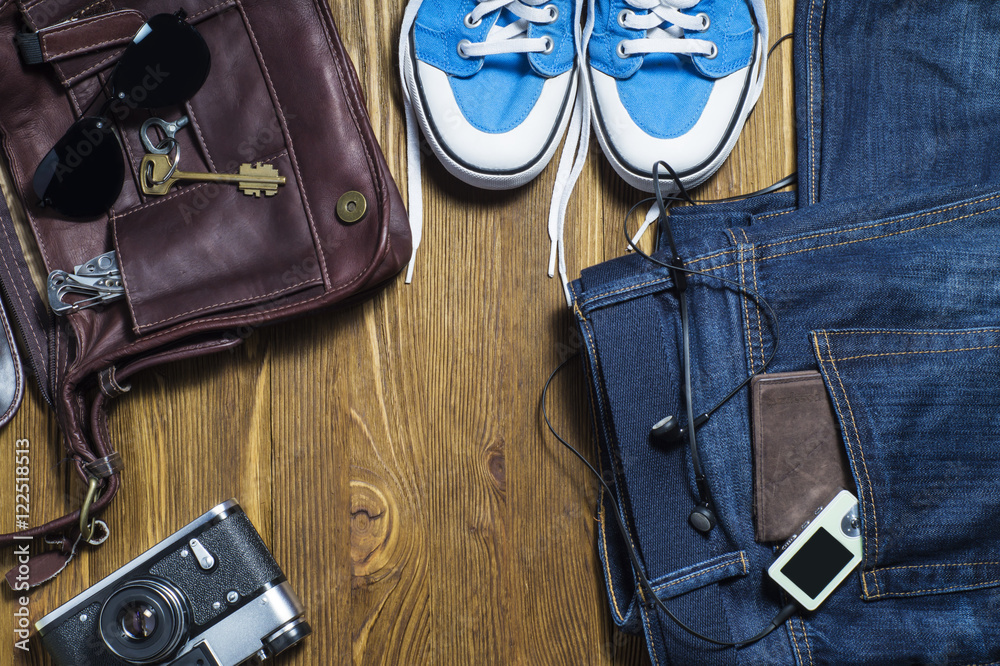 Top view of traveler's casual outfits on blue wooden background. Essential vacation items, travel concept background. Men's casual outfits with man clothing and accessories. Top view of traveler's casual outfits on blue wooden background. Essential vacation items, travel concept background. Men's casual outfits with man clothing and accessories.