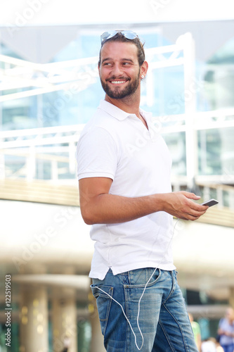 Handsome man holding cellphone outside