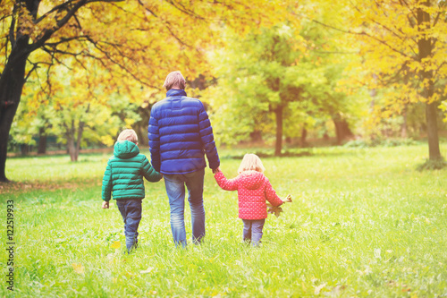 father with two kids walking in autumn fall nature