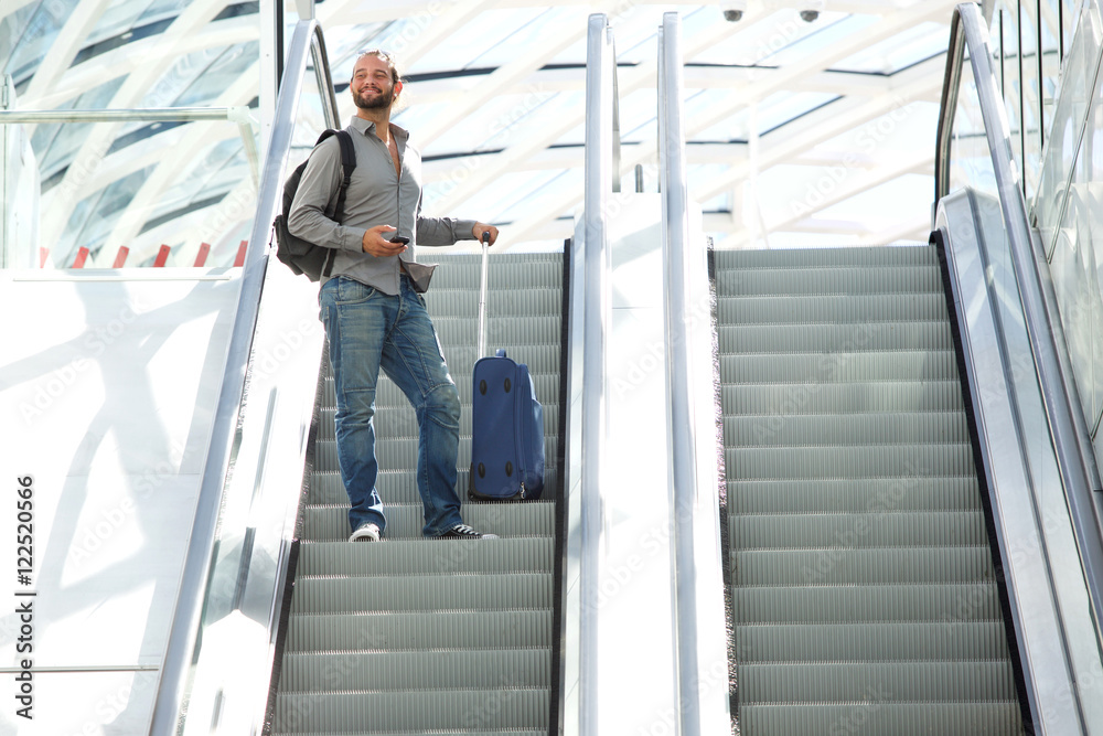 Travel man standing on escalator with bags