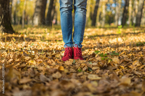 Girl in red shoes standing on fallen leaves
