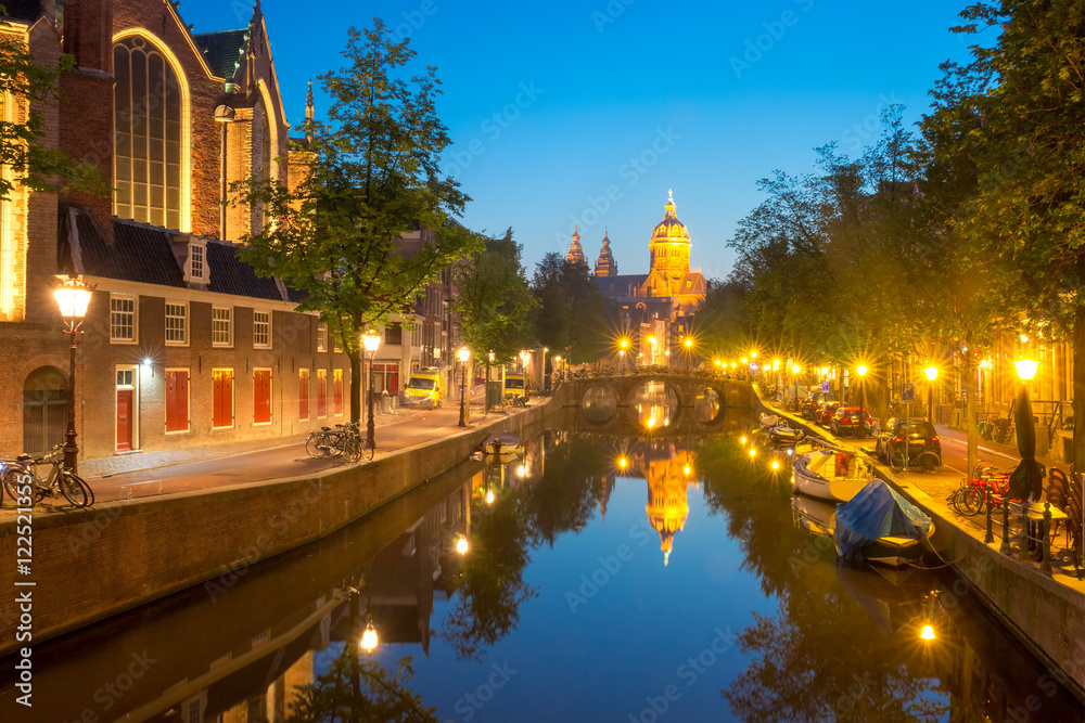 Night red-light district De Wallen, canal, bridge, Basilica of Saint Nicholas and its mirror reflection, Amsterdam, Holland, Netherlands. Long exposure.
