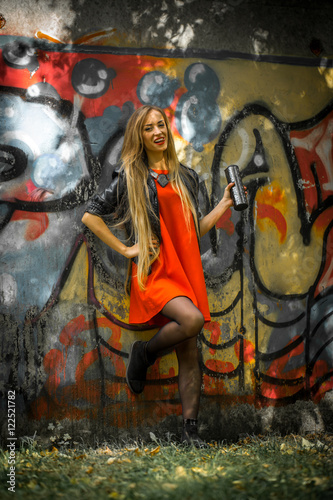 beautiful girl with long hair in a red dress on background of graffiti