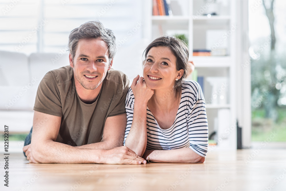 At home, a young couple is lying on the wooden floor At home, a young couple is lying on the wooden floor