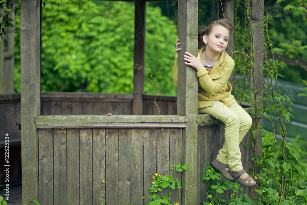 Little girl in yellow suit sits on the wooden pergola Little girl in yellow suit sits on the wooden pergola