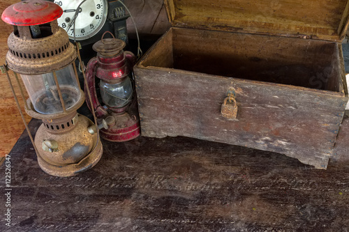 Vintage oil lamp ,old wooden box and alarm clock on old wooden touch-up in still life concept,dark tone.
