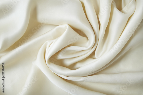 A full page swirl of soft cream silky fabric background texture