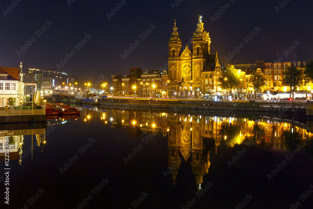 Night city view of Amsterdam canal with Basilica of Saint Nicholas and its mirror reflection in the water, Holland, Netherlands. Long exposure.