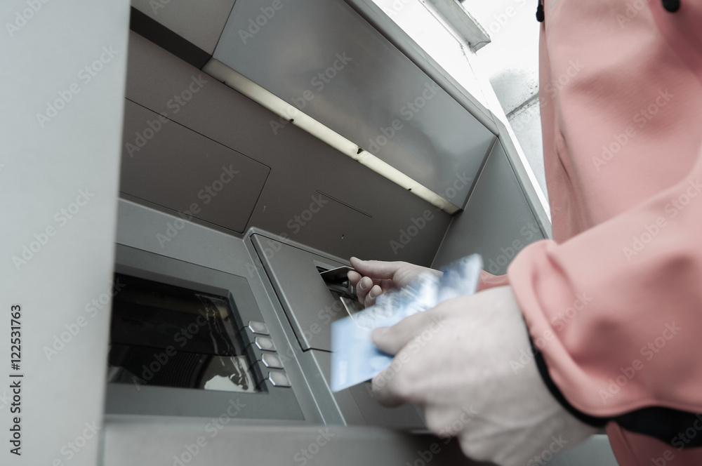 Man at ATM machine with stash of credit and debit cards
