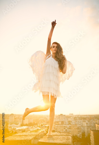 Evening sun shines behind the woman with angel wings