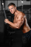 Handsome muscular bodybuilder man doing exercises in gym