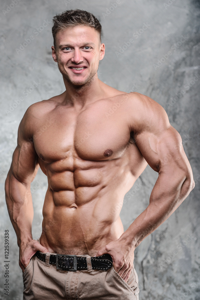 Handsome athletic fitness muscular man posing on a gray backgrou