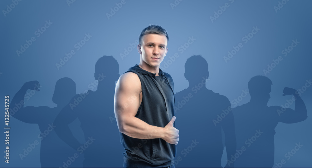 Naklejka premium Young fitness man standing sideways and showing thumb up.