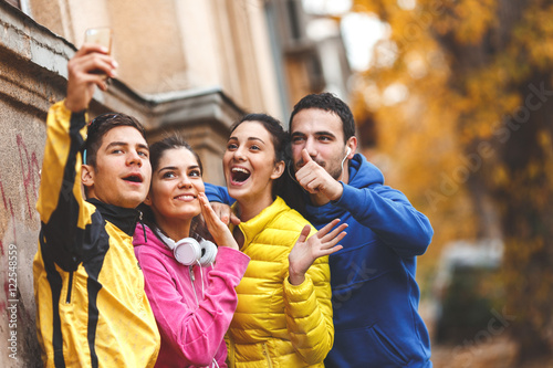 Young friends doing selfie after jogging.They standing on street against the wall.