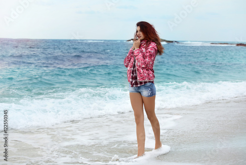 beautiful girl with colorful windbreaker walking on the beach