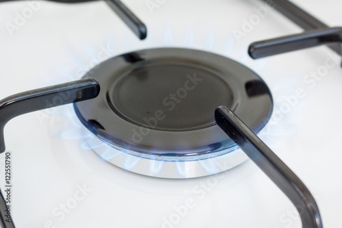 A lit gas ring on the hob of a white cooker