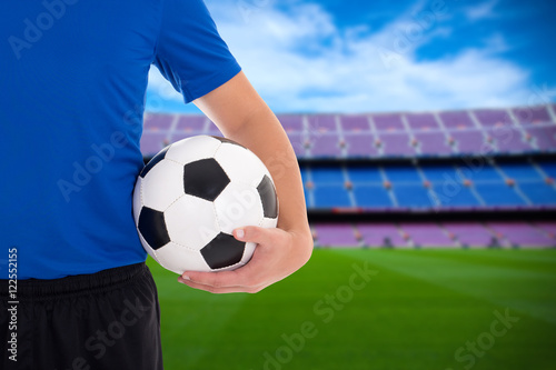 football player holding soccer ball on field of stadium