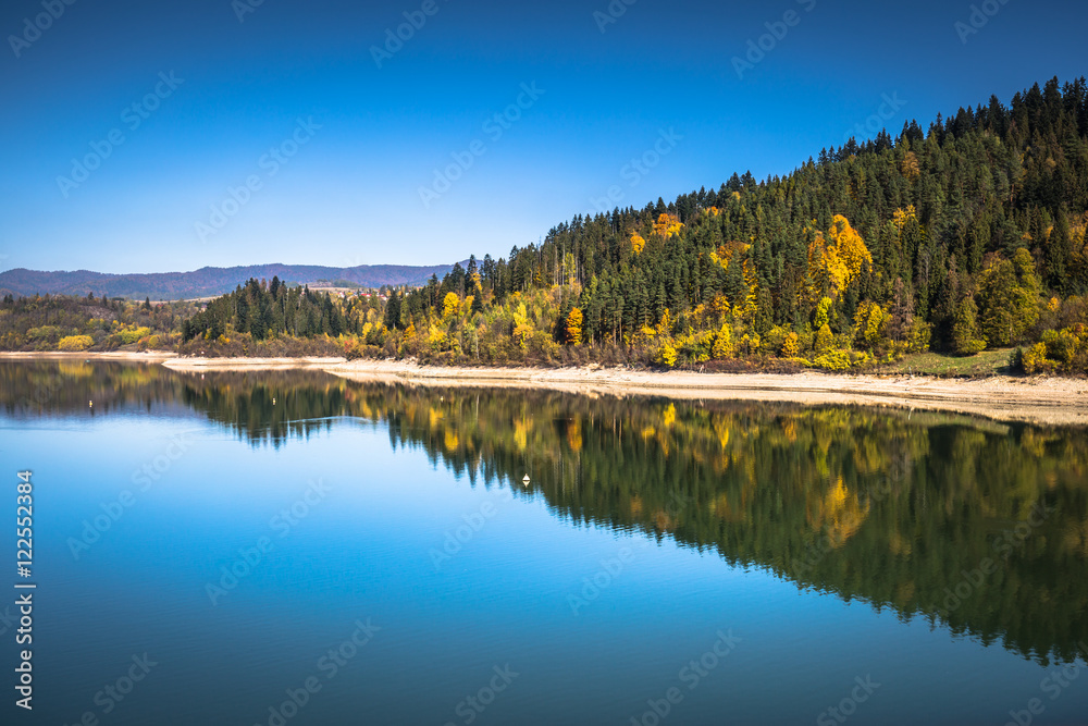 Autumn forest reflected in water. Colorful autumn morning in the