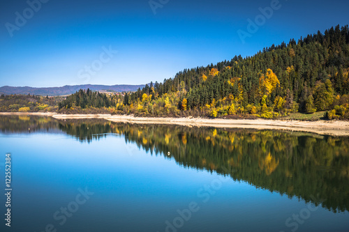 Autumn forest reflected in water. Colorful autumn morning in the