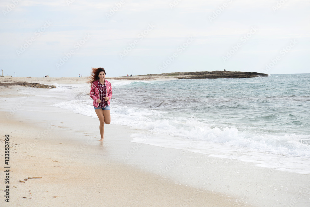 beautiful girl with colorful windbreaker running on the beach
