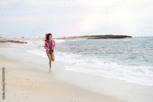beautiful girl with colorful windbreaker running on the beach © gangiskhan