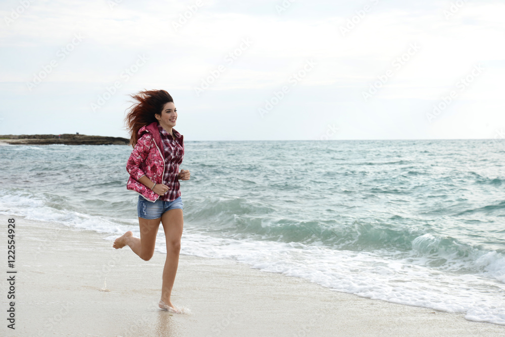 beautiful girl with colorful windbreaker running on the beach