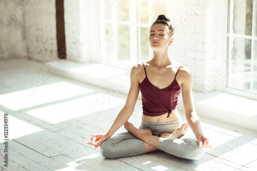 Pretty young girl meditating in the large room photo