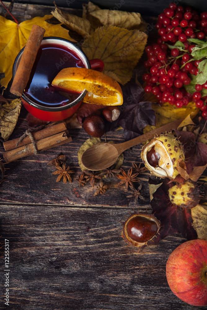 red cup of hot mulled wine in autumn among leaves