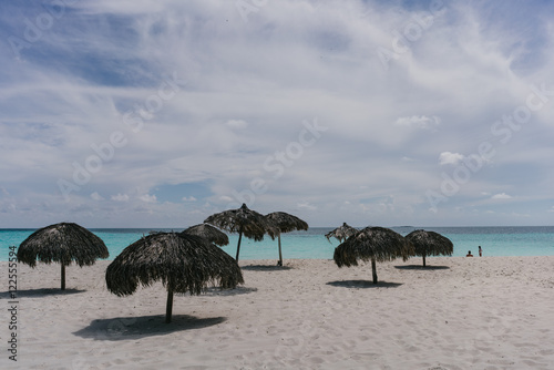 Beach umbrellas made of palm branches on the shores of the Caribbean Sea on the white sand beach of Cayo Largo  Cuba