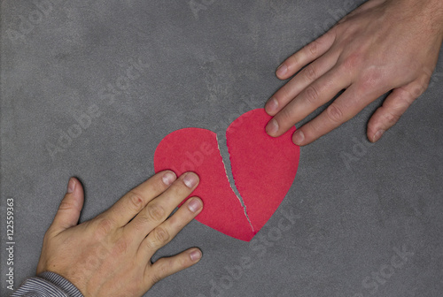 two people tearing paper red heart in half