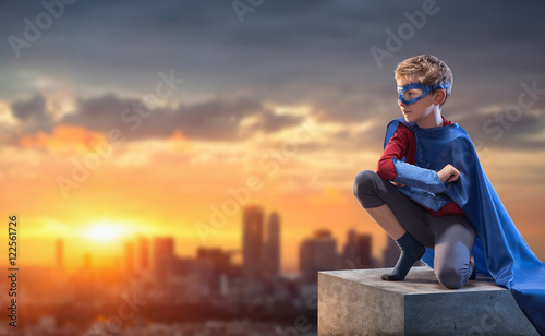 Fotografia At sunset,little boy dressed as superhero watches over the city