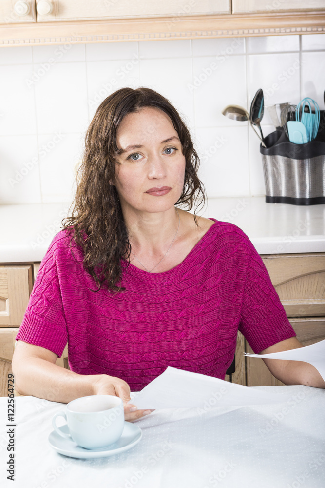 Upset woman with documents in kitchen Upset woman with documents in kitchen